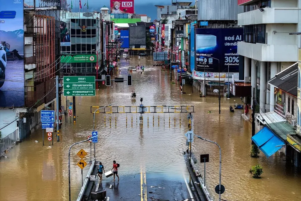 A flooded street in Thailand with residents wading through murky water