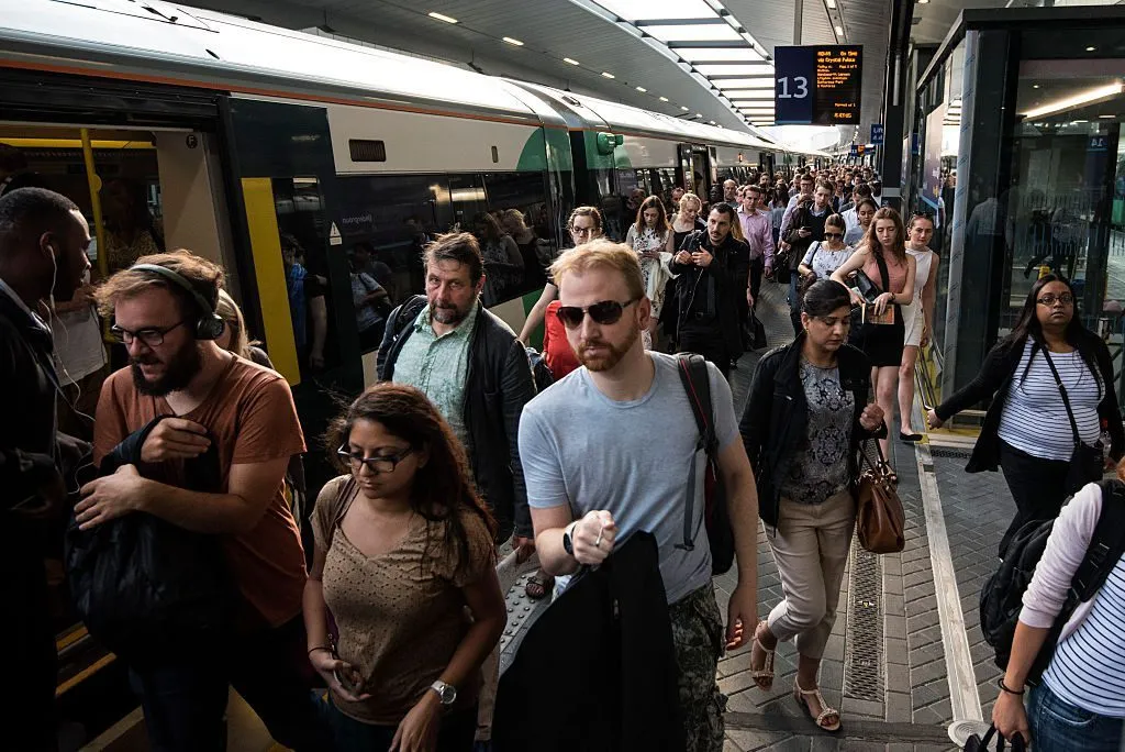 Commuters board a train on a busy UK station platform