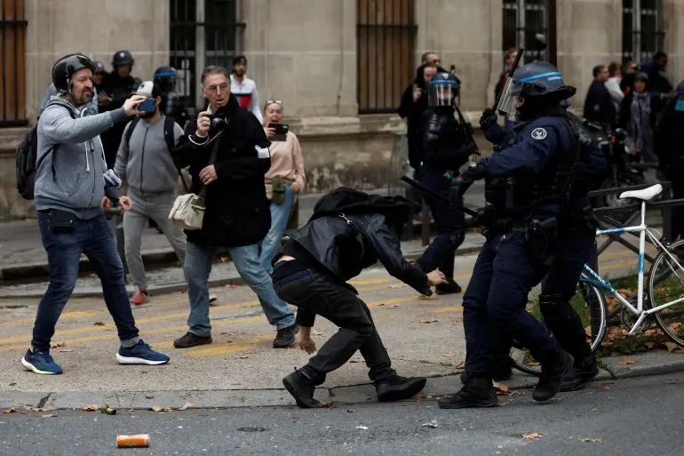 French riot police clash with protesters on a city street