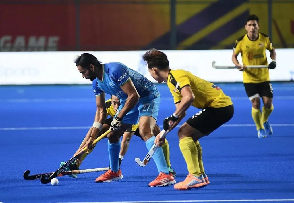 India (blue) in field hockey action against Malaysia (yellow)