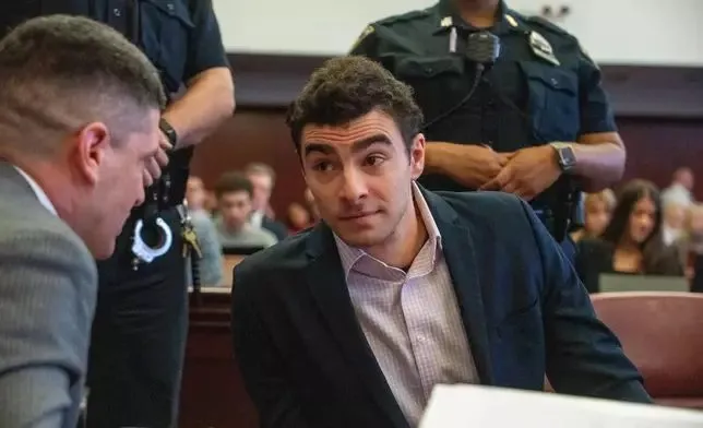 Luigi Mangione seated in a courtroom with officers behind him