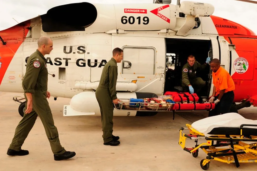 U.S. Coast Guard crew loading a stretcher into a helicopter during a medical evacuation