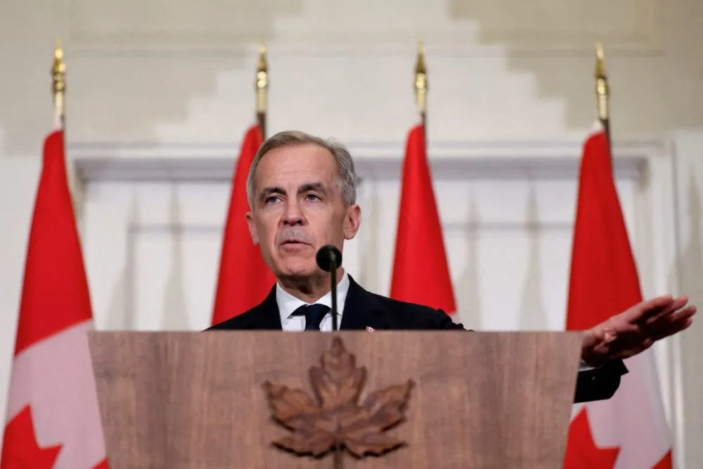 Mark Carney speaks at a podium in front of Canadian flags