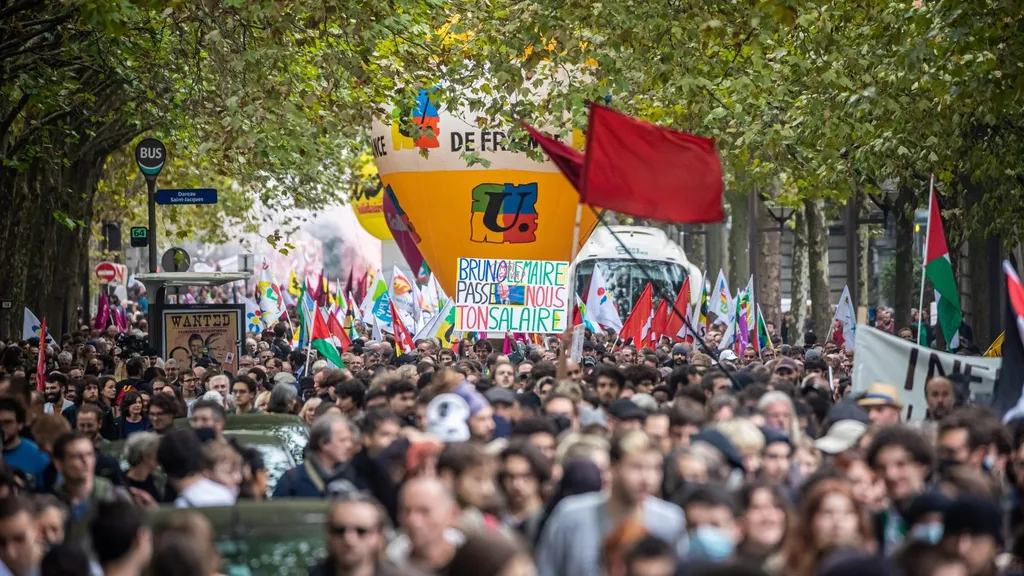 Protesters march with union flags and banners through a Paris street during the French strike mobilisation