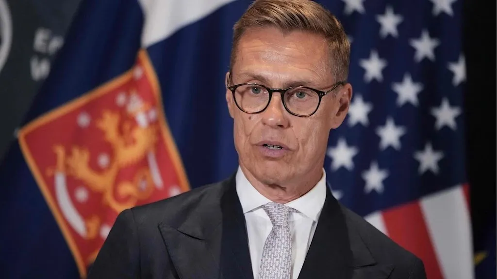 Finnish president Alexander Stubb speaking at a press event in front of the Finnish flag