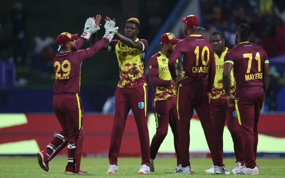 West Indies cricketers celebrate together on the field