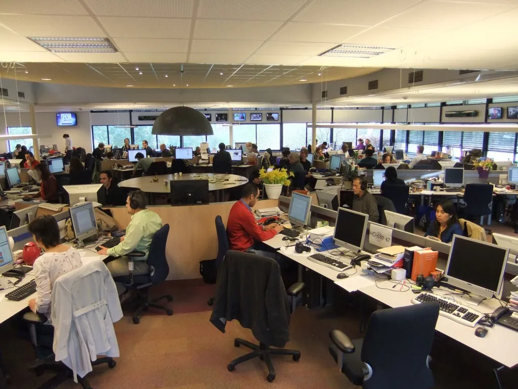 Journalists working at desks with computers in the Radio Netherlands Worldwide newsroom.