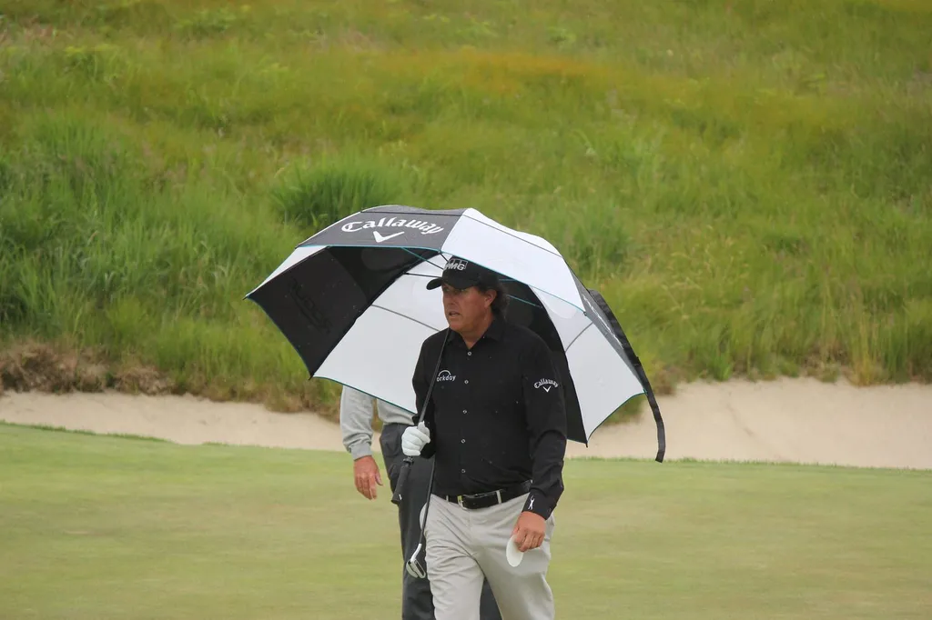 Phil Mickelson holding a Callaway umbrella on the course during the 2018 US Open.