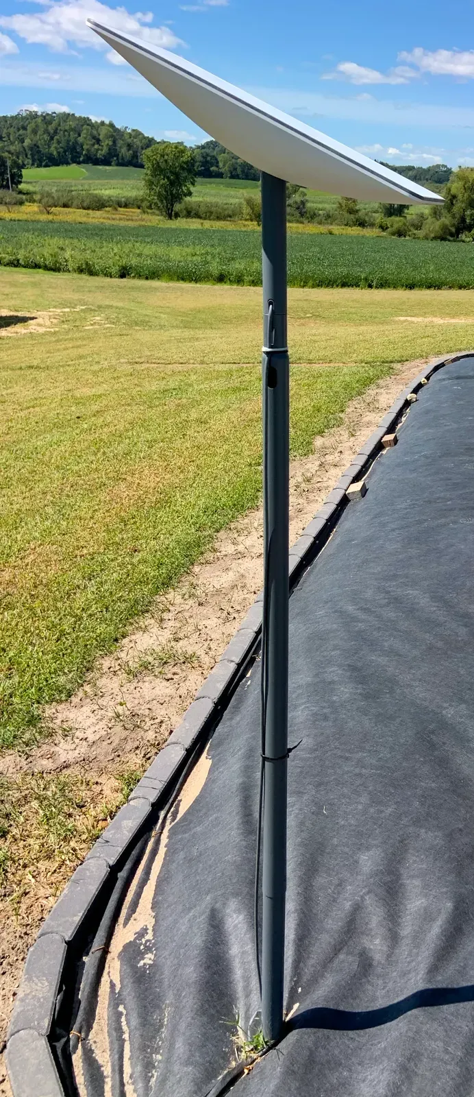 A Starlink satellite dish mounted on a tall pole in an open field